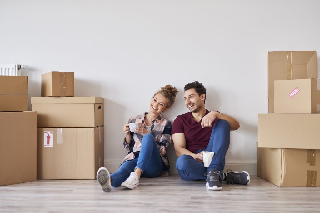 couple sitting on floor near moving boxes
