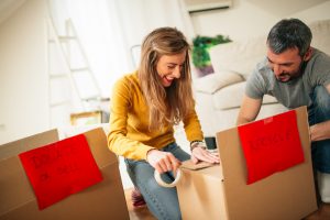 woman and man taping moving boxes for eco-friendly move
