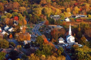 fall foliage surrounds a quaint New England village in an aerial photogrph