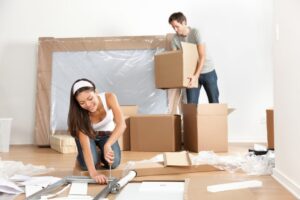 Couple moving in new home house. Young interracial couple in moving in mess. Asian woman, Caucasian man.