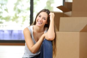 Young woman sitting next to moving boxes inside a home