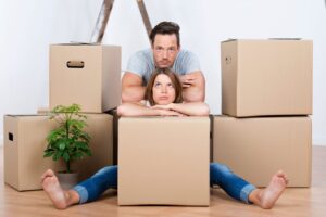 A man and woman sitting on the floor in between moving boxes