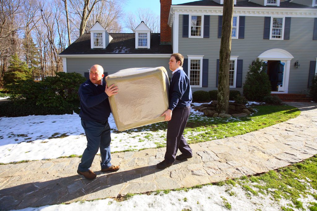 Two Meyer movers outside on a sidewalk carrying a box outside