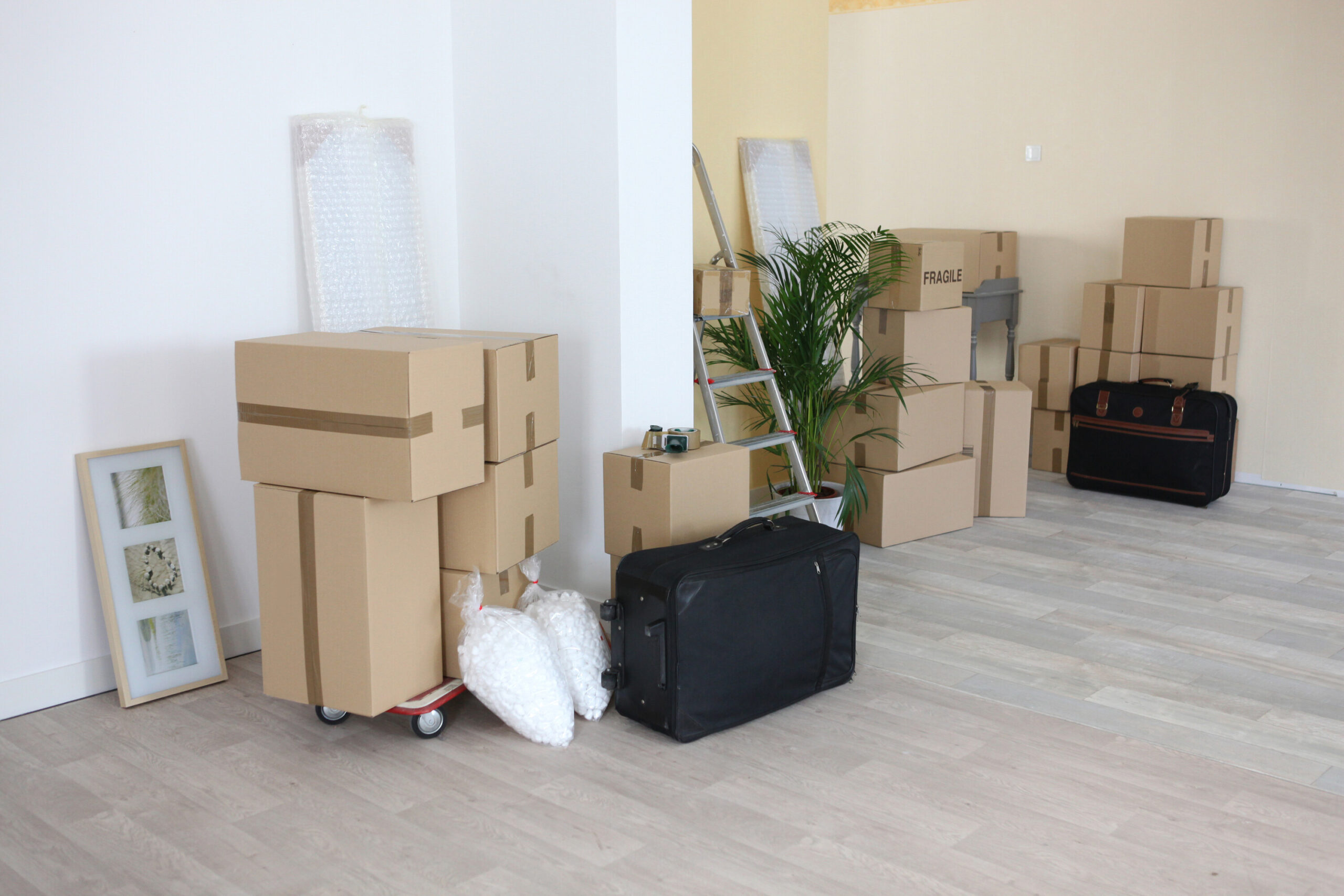 Two rooms of a home with moving boxes stacked up.