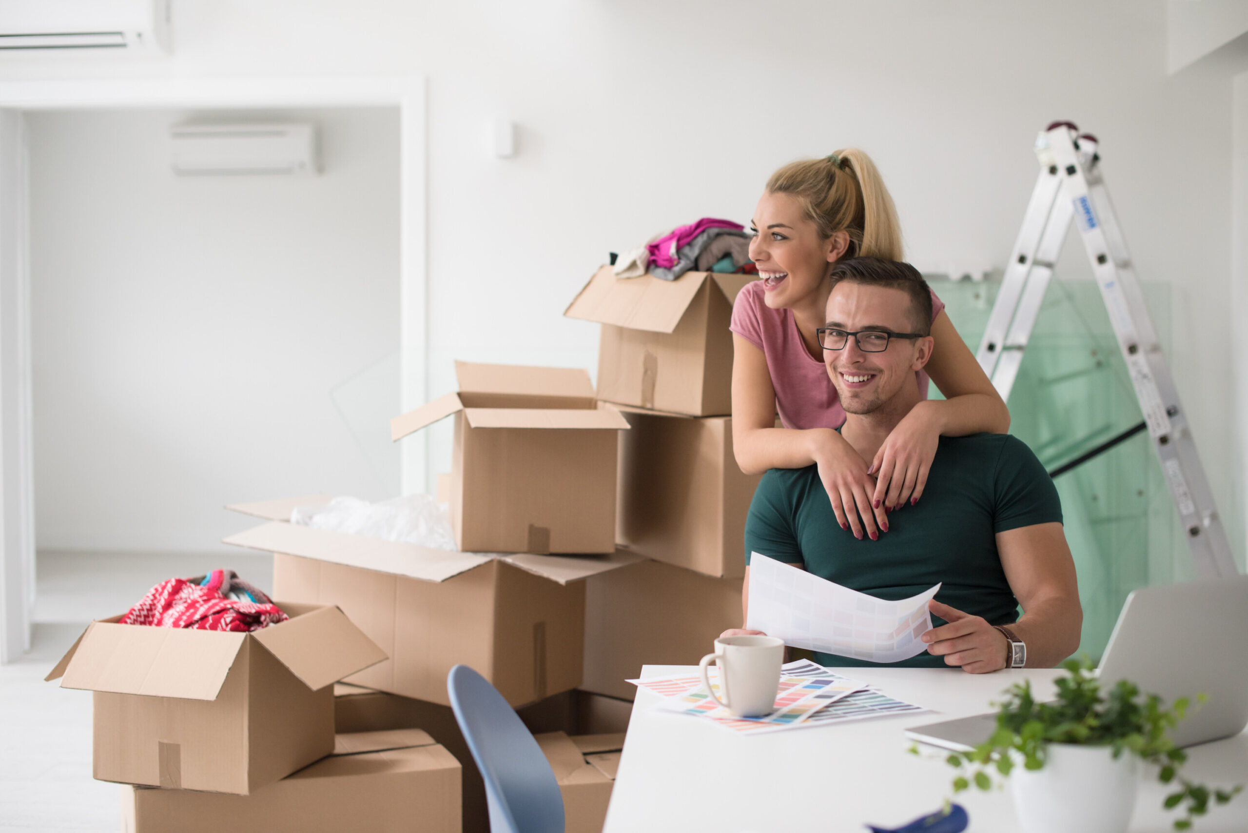 Couple with moving boxes in the background looking at papers while planning move.