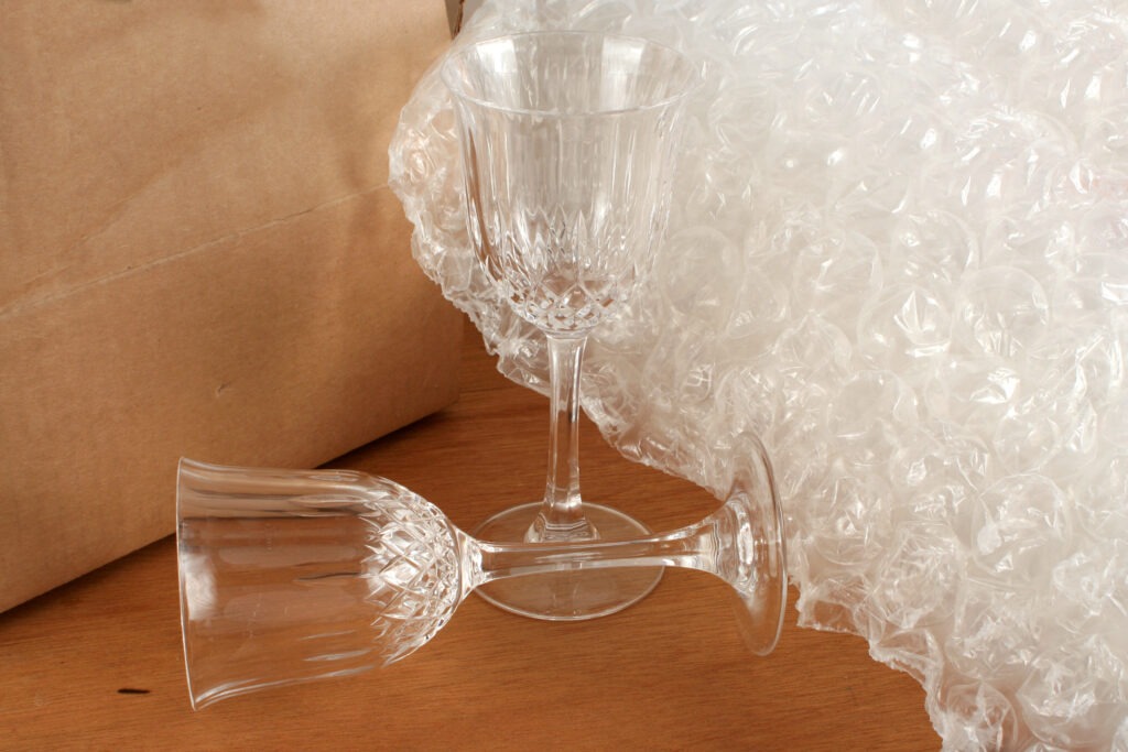 Fragile glasses with bubble wrap sitting in front of a moving box.