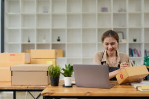 woman packing up her ome office with moving boxes in the back ground.