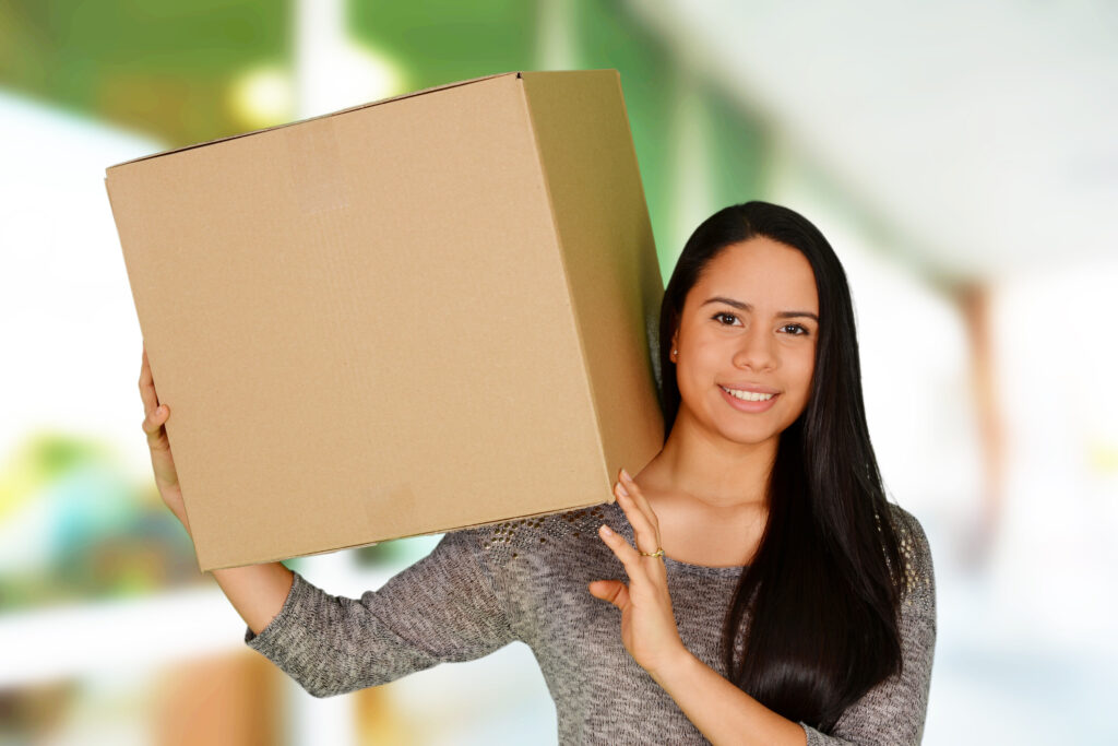 Woman in a plaid shirt holding an essentials moving box