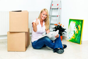 Woman sitting on floor of her apartment with moving boxes